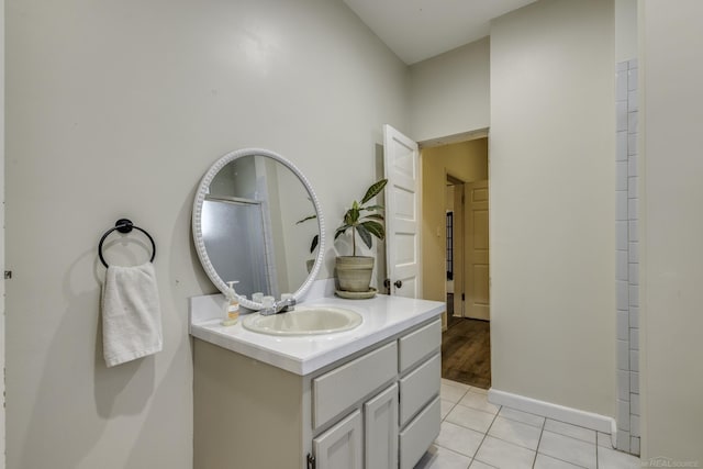 full bath featuring baseboards, walk in shower, tile patterned flooring, and vanity
