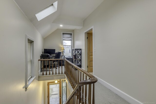 interior space with vaulted ceiling with skylight, an upstairs landing, carpet flooring, baseboards, and recessed lighting