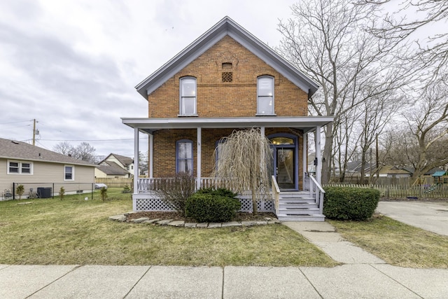 view of front of home featuring a front yard, covered porch, fence, and brick siding