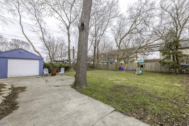 view of yard featuring an outdoor structure, concrete driveway, fence, a detached garage, and a playground