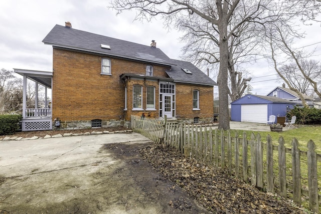 rear view of property with a chimney, an outbuilding, brick siding, and a fenced front yard