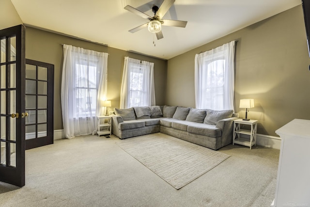carpeted living area featuring baseboards, french doors, a ceiling fan, and plenty of natural light