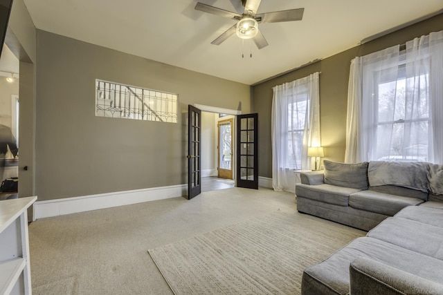 carpeted living area with baseboards and ceiling fan