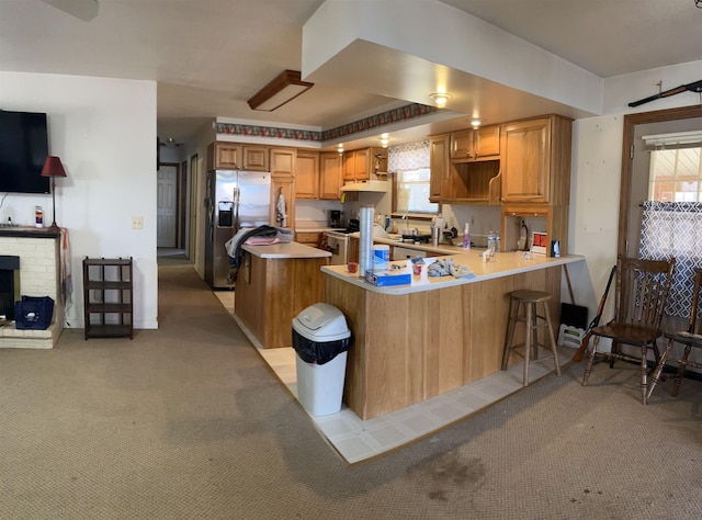 kitchen featuring white electric range oven, light countertops, a peninsula, stainless steel fridge with ice dispenser, and light colored carpet