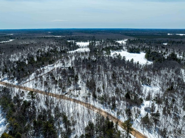 snowy aerial view featuring a wooded view