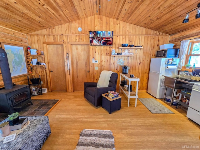 living area with wood ceiling, wood finished floors, a wood stove, and vaulted ceiling