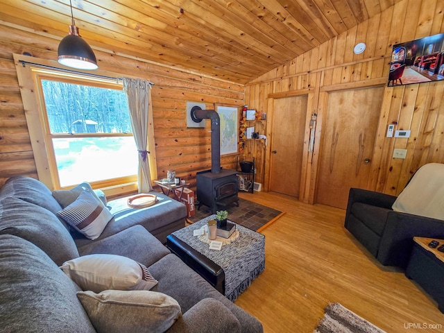 living area with log walls, a wood stove, lofted ceiling, wooden ceiling, and wood finished floors