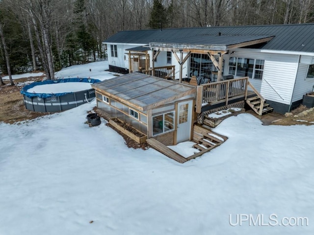 E3117 H44 Hwy, Trenary, MI 49891 - snow covered rear of property featuring a deck, a covered pool, stairway, and metal roof
