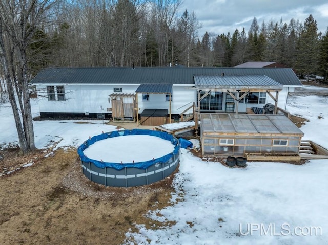 E3117 H44 Hwy, Trenary, MI 49891 - snow covered rear of property with an exterior structure, an outdoor structure, metal roof, and a covered pool