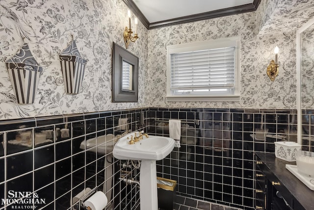 bathroom featuring tile walls, wallpapered walls, ornamental molding, and wainscoting