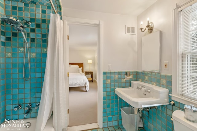 full bath with tile walls, toilet, a wainscoted wall, visible vents, and shower / bath combo