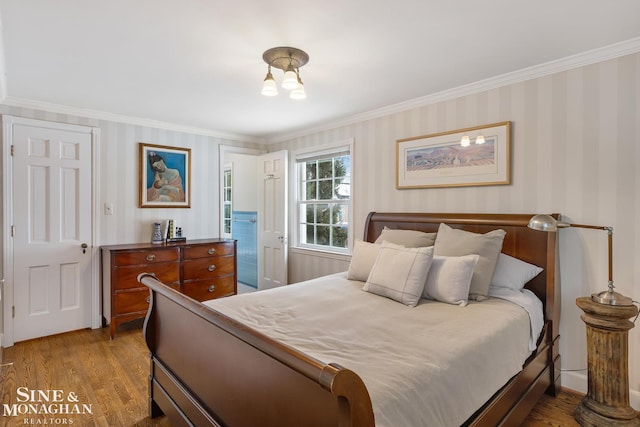 bedroom featuring wallpapered walls, crown molding, and wood finished floors