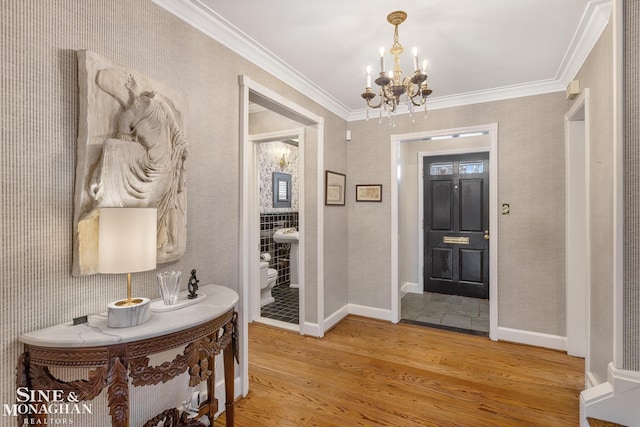entrance foyer with light wood-type flooring, an inviting chandelier, ornamental molding, baseboards, and wallpapered walls