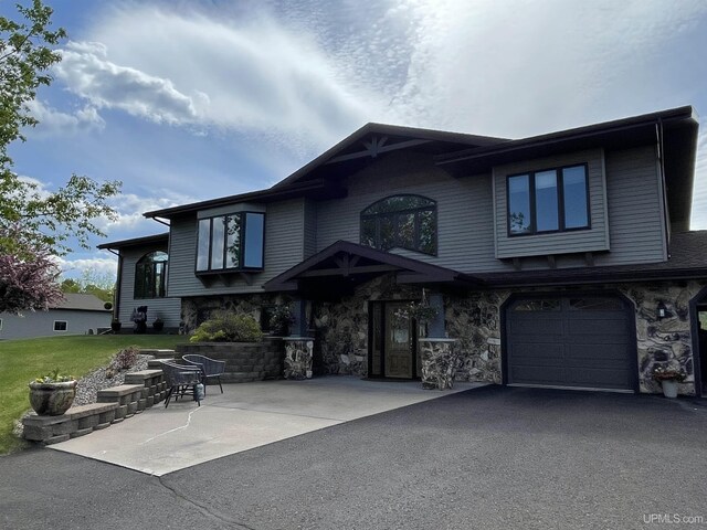 661 S Range Rd, Ironwood, MI 49938 - view of front facade with a garage, asphalt driveway, a front yard, and stone siding