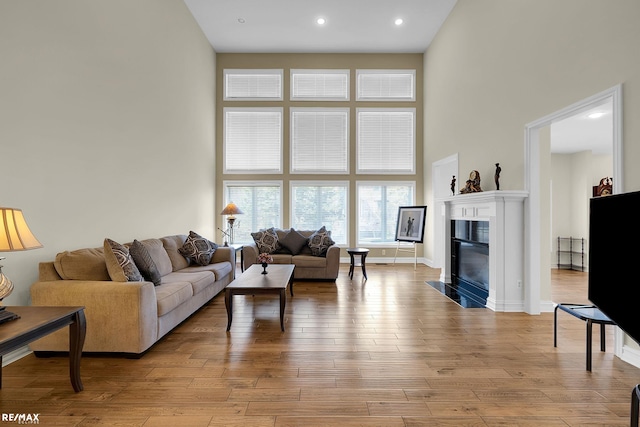 55763 Omni Dr, Shelby, MI 48315 - living area featuring baseboards, recessed lighting, a fireplace, a high ceiling, and light wood finished floors