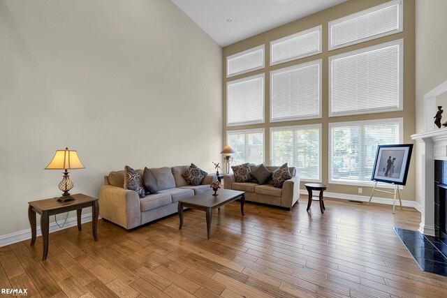 55763 Omni Dr, Shelby, MI 48315 - living area with light wood-style flooring, a premium fireplace, a high ceiling, and baseboards