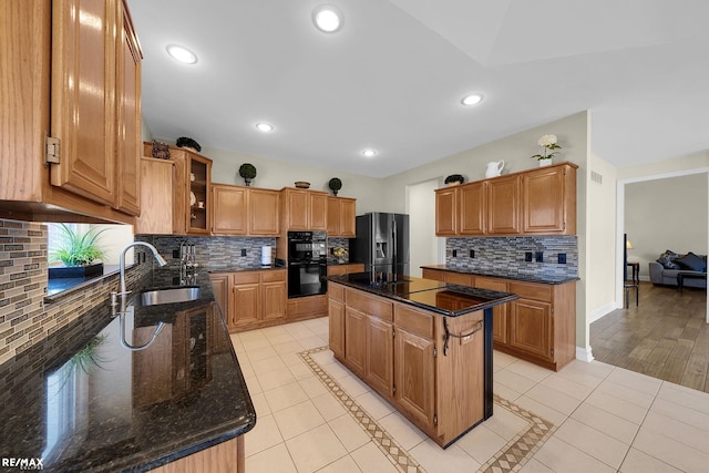 55763 Omni Dr, Shelby, MI 48315 - kitchen with light tile patterned floors, a kitchen island, black appliances, dark stone counters, and a sink