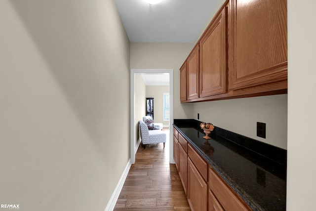 55763 Omni Dr, Shelby, MI 48315 - kitchen with brown cabinetry, dark stone counters, light wood-style floors, and baseboards