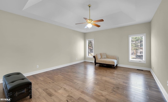 55763 Omni Dr, Shelby, MI 48315 - sitting room with baseboards, a ceiling fan, visible vents, a tray ceiling, and wood finished floors