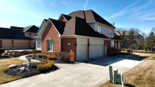 55763 Omni Dr, Shelby, MI 48315 - view of home's exterior featuring an attached garage, a shingled roof, concrete driveway, and brick siding