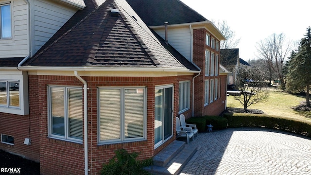 55763 Omni Dr, Shelby, MI 48315 - view of side of home featuring a patio, a shingled roof, and brick siding