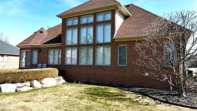 55763 Omni Dr, Shelby, MI 48315 - back of house featuring a yard, a shingled roof, and brick siding