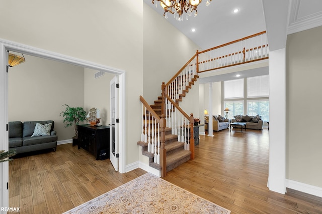 55763 Omni Dr, Shelby, MI 48315 - stairs featuring hardwood / wood-style floors, a high ceiling, an inviting chandelier, and visible vents