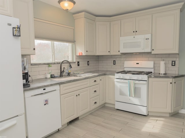 kitchen with tasteful backsplash, white appliances, a sink, and light wood finished floors