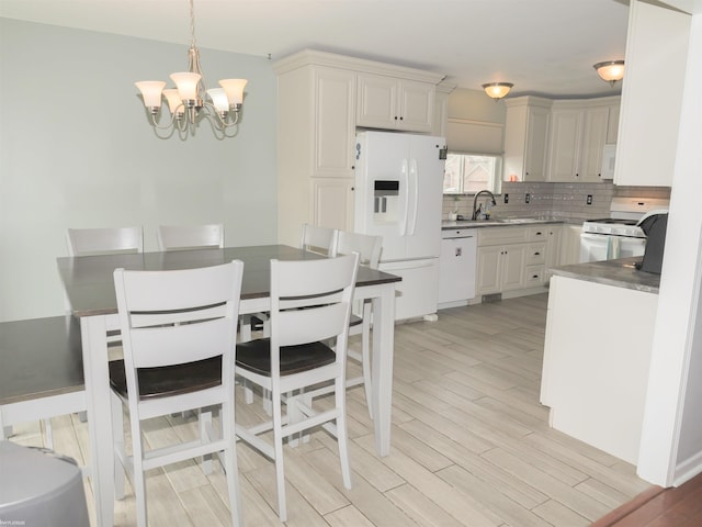 kitchen with white appliances, wood finish floors, a chandelier, a sink, and decorative backsplash