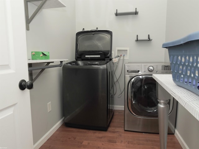 clothes washing area featuring washer and dryer, laundry area, dark wood-style flooring, and baseboards