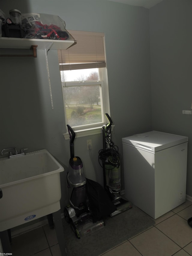 laundry area featuring laundry area, a sink, and light tile patterned flooring