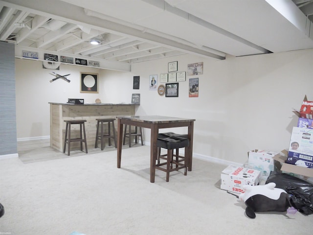 carpeted dining area featuring indoor bar, beamed ceiling, and baseboards