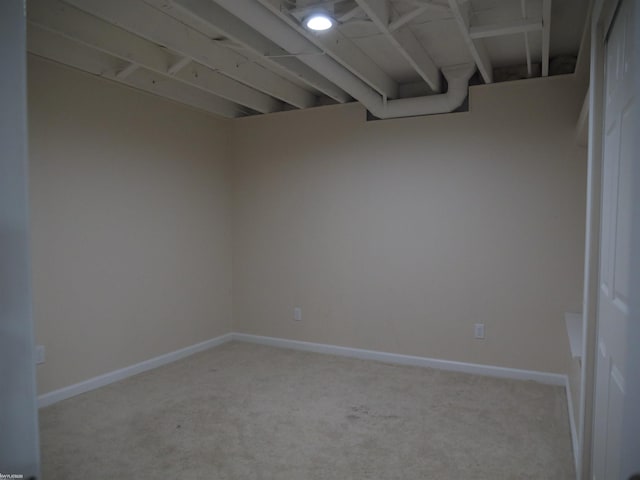 empty room featuring baseboards and light carpet