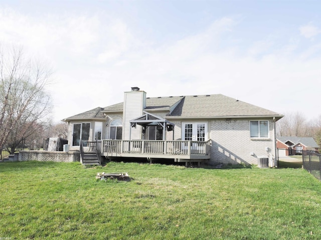 rear view of house featuring a yard, a chimney, fence, brick siding, and a wooden deck