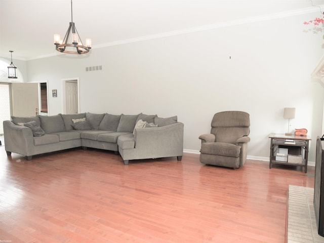 living room featuring light wood-type flooring, ornamental molding, visible vents, a chandelier, and baseboards