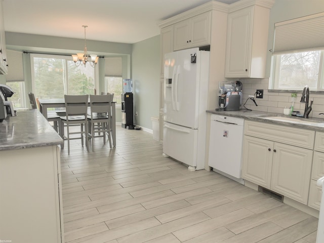 kitchen featuring tasteful backsplash, an inviting chandelier, a sink, white appliances, and light wood-style floors