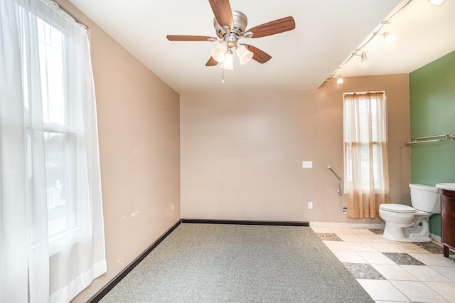 spare room featuring rail lighting, baseboards, and ceiling fan