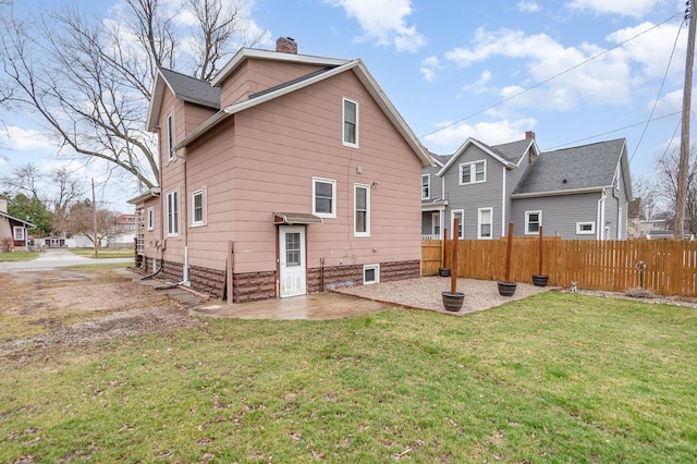 back of property featuring a lawn, a patio, a chimney, and fence
