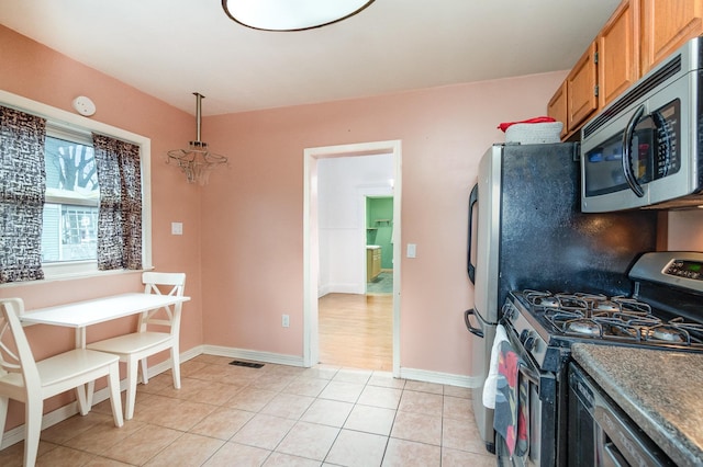 kitchen featuring brown cabinets, light tile patterned floors, stainless steel appliances, baseboards, and visible vents