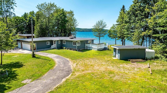 view of front of property featuring a garage, a front yard, driveway, and a water view
