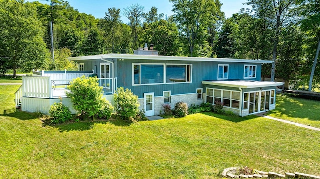 rear view of house featuring a sunroom and a lawn