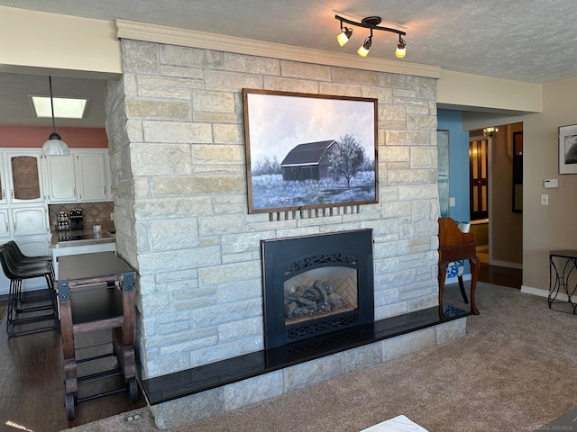 carpeted living room with baseboards, a fireplace, and a textured ceiling