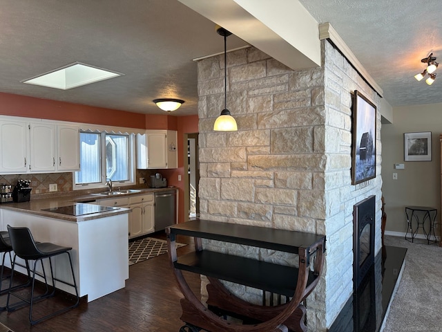 kitchen featuring a peninsula, white cabinetry, backsplash, a textured ceiling, and stainless steel dishwasher