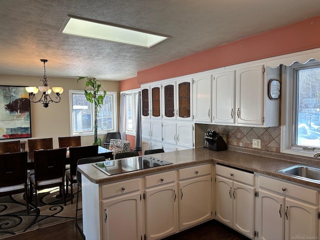 kitchen with a sink, white cabinets, and a peninsula