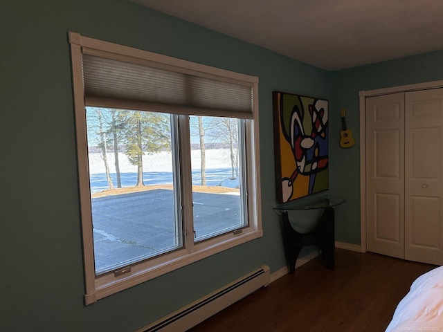 bedroom with a baseboard radiator, a closet, baseboards, and dark wood finished floors