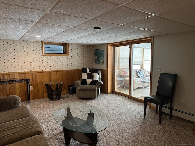 carpeted living area with baseboard heating, a drop ceiling, wallpapered walls, and a wainscoted wall