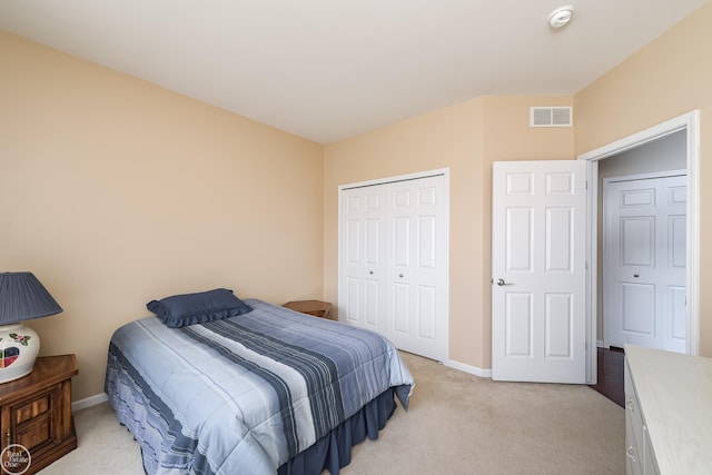 bedroom with a closet, light colored carpet, baseboards, and visible vents