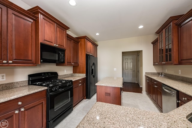 kitchen featuring light stone countertops, glass insert cabinets, black appliances, and recessed lighting
