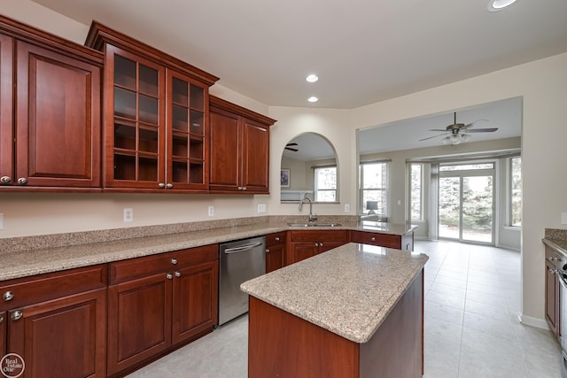 kitchen featuring arched walkways, dishwasher, a sink, ceiling fan, and a kitchen island