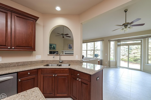 kitchen featuring stainless steel dishwasher, a sink, a ceiling fan, and plenty of natural light